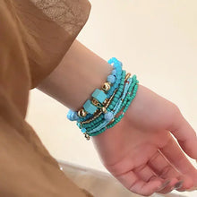 Womans arm with turquoise and gold resin rice bead bracelet, square stones