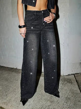 Black rhinestone embellished wide leg jeans featuring sparkling star-like details on denim fabric