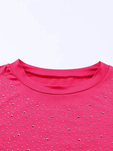 A vibrant pink long sleeve bodysuit with a round neck adorned with sparkling silver rhinestones