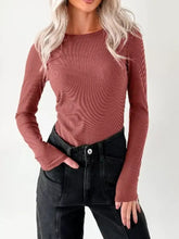 A dusty rose ribbed long sleeve fitted bodysuit with a round neckline and fingerless cuffs