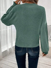 Green ribbed knit sweater with dark wash skinny jeans