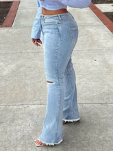 Light-wash denim ripped knee flare jeans with distressed knee patch and frayed hems for casual wear