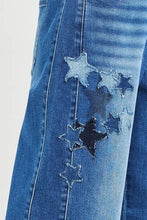 Blue denim cropped barrel jeans with risen elastic band and stitched star patch appliqués in varying blue and black shades