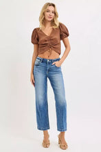 Brown ribbed crop top with puffed sleeves and front tie detail paired with high rise medium blue wash jeans