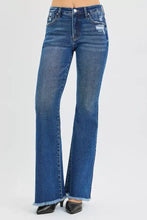 Risen high rise flare jeans in blue denim with distressed details and frayed hems showcasing a high rise flare style