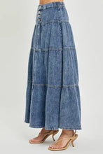 A medium-wash denim risen high rise ruffle long skirt with tiered flared design and button closure at the waist