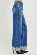 Blue denim risen high rise wide leg jeans with cuffed hem, distressed frayed edges, and classic stitching detail