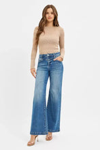 Beige lace long-sleeve top with subtle geometric pattern paired with risen high rise wide leg jeans back view