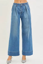 Blue denim risen slouchy wide leg jeans featuring a high waist, pleated front, and rolled cuffs for a relaxed fit