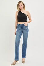 High-waisted medium blue denim jeans with crease line and subtle distressing for a polished aesthetic at the natural waistline