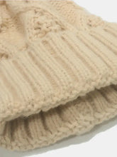Close-up of beige roll rim cable-knit beanie hat