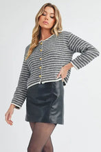 Round neck cardigan with gold buttons and black leather skirt