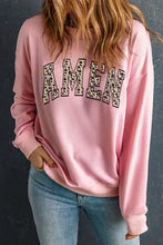 Woman in dropped shoulder AMEN graphic sweatshirt and light jeans