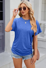 Woman in round neck flutter sleeve t-shirt with side ruching and denim shorts
