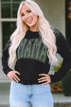 Woman in long sleeve MAMA graphic sweatshirt and blue jeans