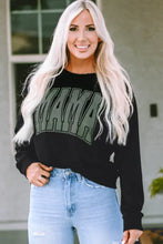 Woman in long sleeve MAMA graphic sweatshirt and ripped jeans