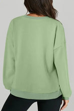 Woman in solid light green round neck long sleeve sweatshirt