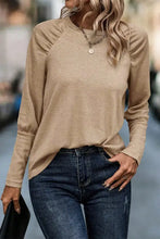Round neck long sleeve tan top with gathered shoulders, paired with dark jeans