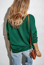 Woman in round neck long sleeve green top and ripped jeans with bag