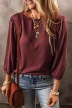 Woman in round neck puff sleeve maroon top with jeans and accessories