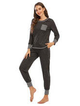 Dark gray round neck top and pants lounge set with white striped accents on chest pocket cuffs and hem