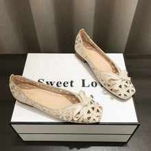 Pair of beige round toe flats with laser-cut patterns and bow