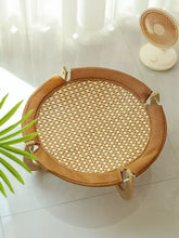 Round elevated woven pet bed with tan border and sturdy wood legs