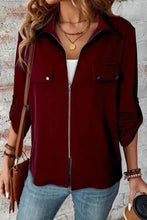 Burgundy zip-up jacket with pocket details and layered necklaces