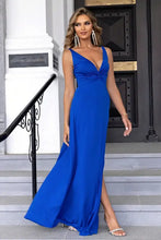 Woman in royal blue twisted slit plunge maxi dress with thigh-high slit