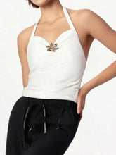 White ruched halter neck cami with gold-toned floral brooch at center featuring a halter neck design