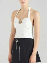 White ruched halter neck cami with textured fabric and ornate gold-toned brooch at the center