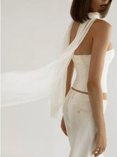 A flowing white sheer scarf elegantly drapes over the back of a ruched tube top strapless corset
