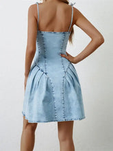 Light blue denim dress with ruched zip and spaghetti strap featuring a fitted corset-style back view