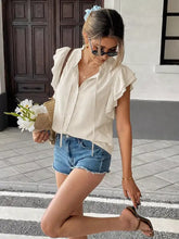 A cream-colored ruffle sleeve tie-neck blouse with button-down front and drawstring hem for elegant wear