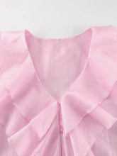 A delicate pink ruffle trimmed long sleeve blouse with layered ruffled collar and subtle pearl buttons