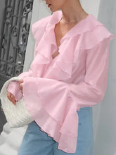 A soft pink ruffle trimmed long sleeve blouse in lightweight flowing fabric with layered ruffles on neckline and sleeves