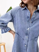 A light blue denim dress featuring a ruffled cuff button-down front closure in a stylish shirt dress design