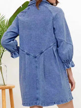 A medium-wash blue denim dress with long sleeves, collar, and ruffled cuff button-down details