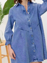 A medium-wash blue denim dress featuring a ruffled cuff button-down design with long sleeves and subtle stitching details