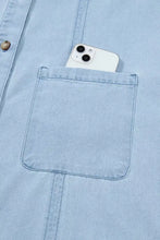 White iphone 13 with dual cameras peeking from pocket of light blue machine wash cold ruffled edge collared denim dress