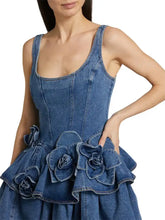 Denim dress with a fitted bodice and layered scoop neck featuring ruffled floral embellishments at the waist