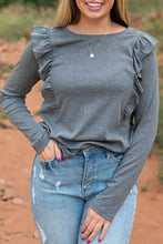 Woman in ruffled round neck long sleeve T-shirt and distressed jeans