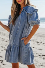 A light blue denim mini dress with ruffled puff sleeves and a tiered skirt featuring side pockets