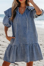 Blue denim mini dress with ruffled sleeves and hem featuring v-neckline with drawstrings in a puff sleeve style