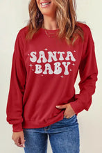 Woman in red Santa Baby round neck long sleeve sweatshirt and jeans