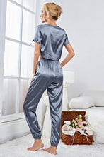 A sleek satin-gray two-piece pajama set with short sleeve cropped top and loose-fitting jogger pants suitable for lounging