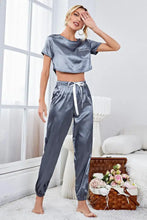 A shimmering gray satin short sleeve crop top with chest pocket and matching drawstring jogger pants lounge set