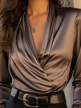 A sleek satin surplice long sleeve blouse in bronze with a draped front and deep v-neckline