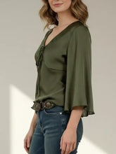Olive green satin tie-front blouse with bell sleeves showcasing elegant and soft fabric texture