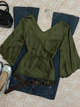 Olive green satin tie-front blouse with bell sleeves and a tied waistband for elegant styling